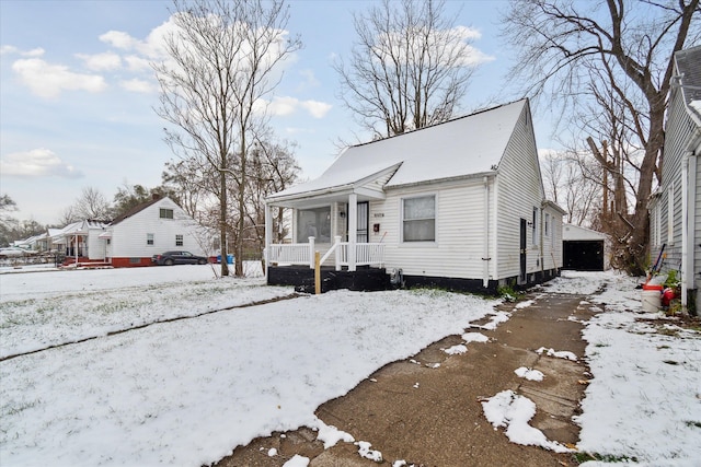 bungalow with a porch, a garage, and an outdoor structure