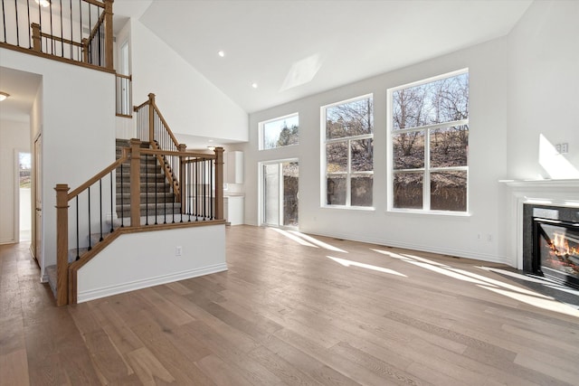 unfurnished living room featuring a towering ceiling and light hardwood / wood-style floors