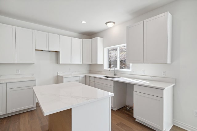 kitchen featuring light stone countertops, sink, white cabinets, a center island, and dark hardwood / wood-style floors