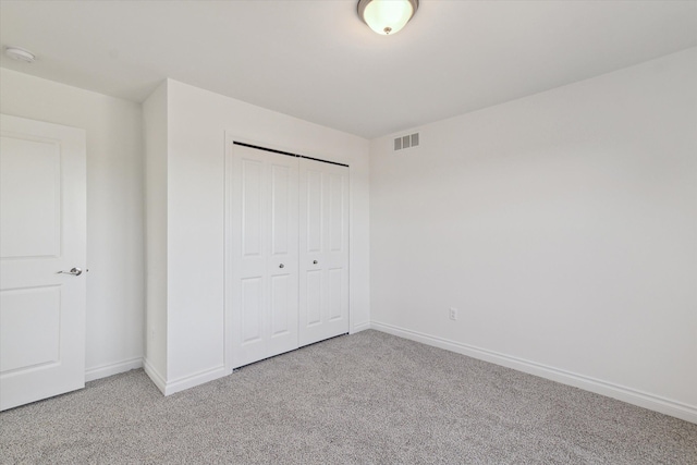 unfurnished bedroom with light colored carpet and a closet