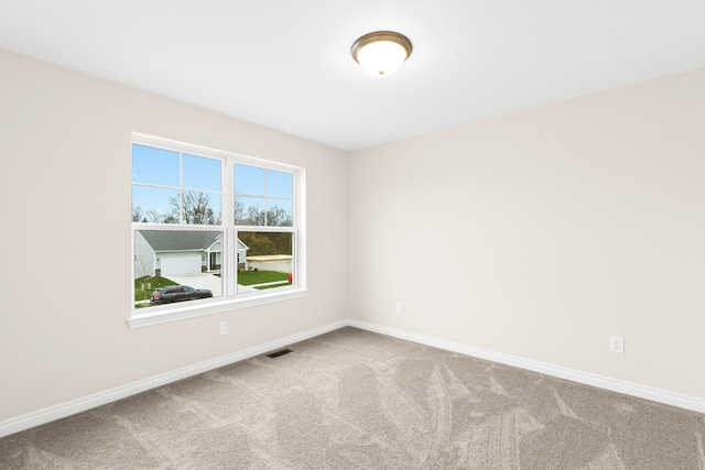 carpeted spare room with visible vents and baseboards