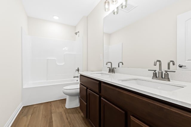 full bath featuring double vanity, a sink, toilet, and wood finished floors