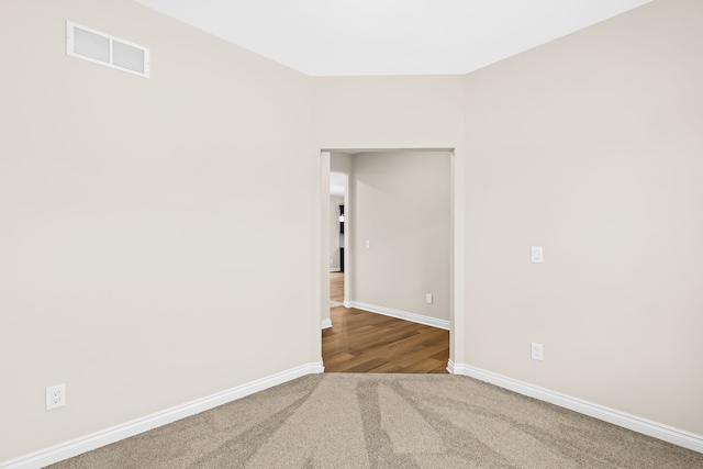 empty room featuring carpet floors, visible vents, and baseboards