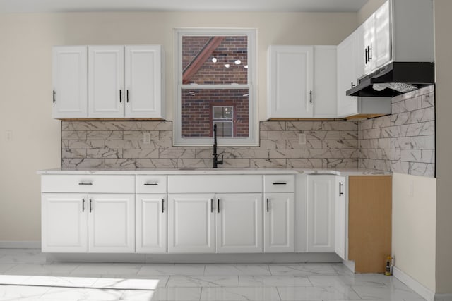 kitchen featuring backsplash, sink, and white cabinetry