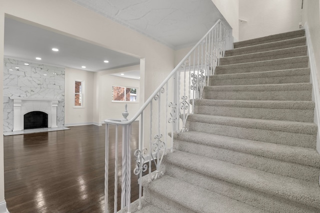 stairs featuring a premium fireplace and hardwood / wood-style flooring