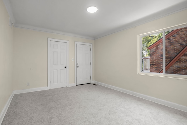 unfurnished bedroom with multiple closets, crown molding, and carpet flooring