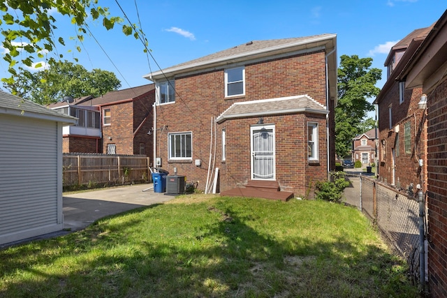 rear view of house with central AC, a patio, and a yard