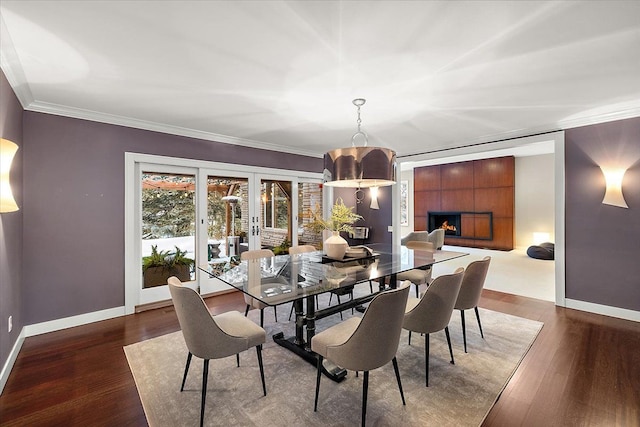 dining space with a tile fireplace, crown molding, dark hardwood / wood-style floors, and french doors