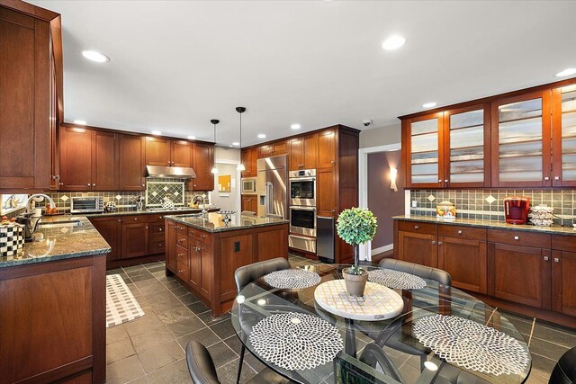 kitchen featuring pendant lighting, sink, a center island with sink, and dark stone countertops