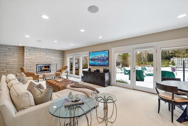 carpeted living room with a stone fireplace and french doors