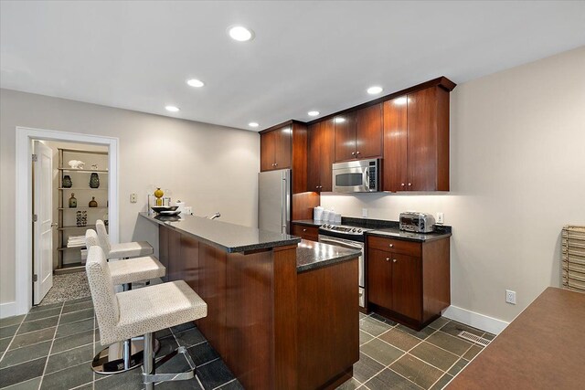 kitchen with stainless steel appliances, a breakfast bar, kitchen peninsula, and a center island