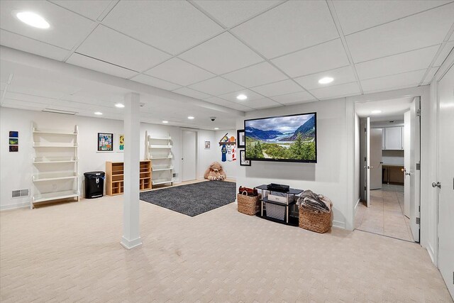 carpeted living room featuring a drop ceiling