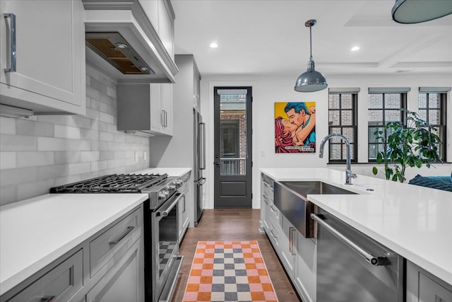 kitchen featuring light countertops, high end appliances, a sink, and custom range hood