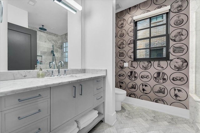 bathroom featuring wallpapered walls, baseboards, toilet, a tile shower, and vanity