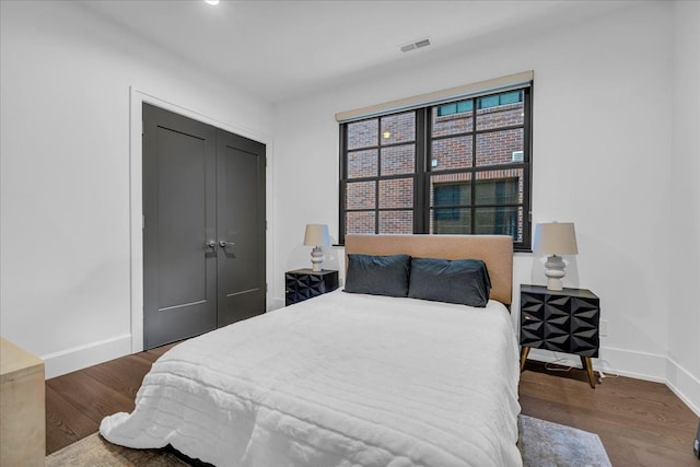 bedroom featuring baseboards, a closet, visible vents, and wood finished floors