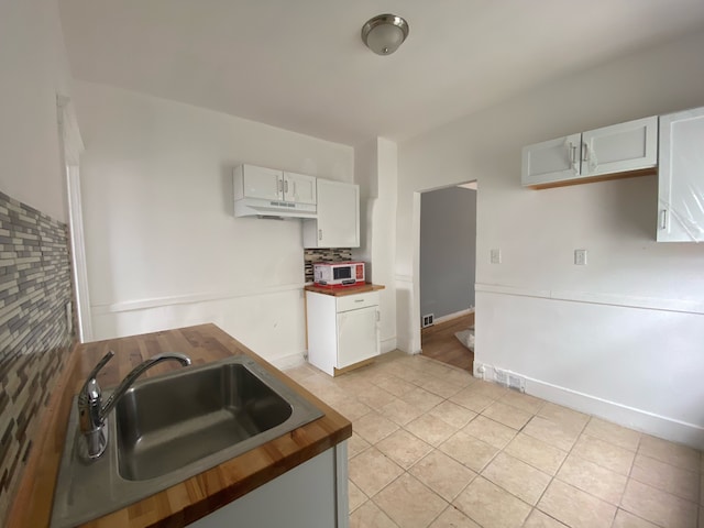 kitchen with white cabinets, decorative backsplash, light tile patterned flooring, and sink