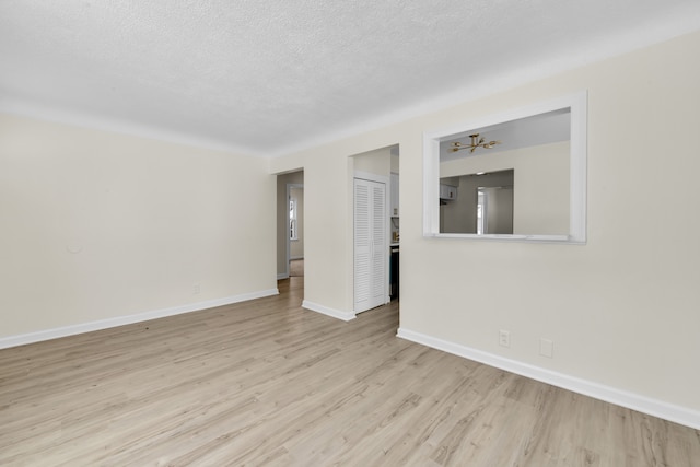 spare room featuring a textured ceiling and light hardwood / wood-style floors