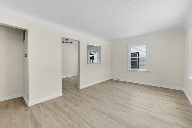 unfurnished room with a textured ceiling and light hardwood / wood-style flooring