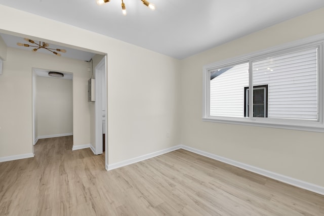 unfurnished room with light hardwood / wood-style floors and a notable chandelier