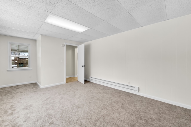 basement featuring baseboard heating, carpet floors, and a paneled ceiling