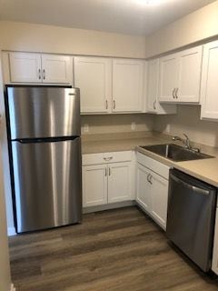 kitchen with stainless steel appliances, dark wood-type flooring, white cabinets, and sink