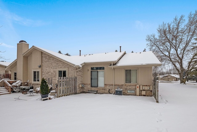 snow covered house featuring central AC unit