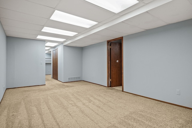 basement featuring light colored carpet and a paneled ceiling