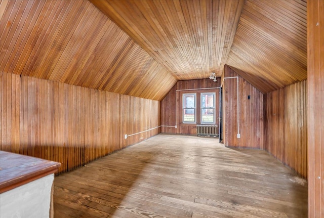 additional living space with wood ceiling, hardwood / wood-style floors, vaulted ceiling, wooden walls, and radiator heating unit