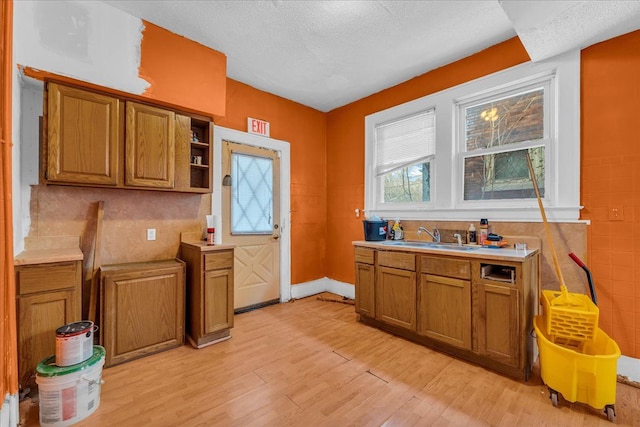 kitchen with a textured ceiling, light hardwood / wood-style floors, decorative backsplash, and sink