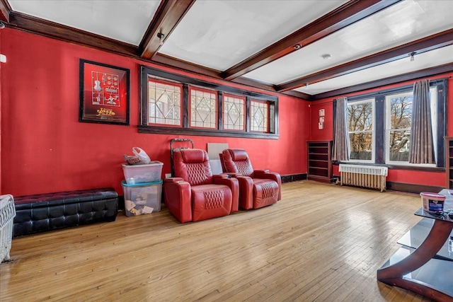 home theater room featuring radiator, beamed ceiling, and light hardwood / wood-style flooring