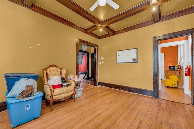 sitting room featuring coffered ceiling, light hardwood / wood-style flooring, ceiling fan, ornamental molding, and beamed ceiling