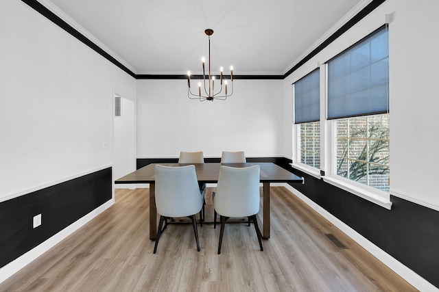 dining space featuring light hardwood / wood-style flooring, ornamental molding, and an inviting chandelier