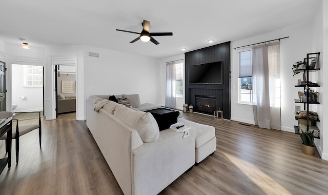 living room with ceiling fan, a fireplace, hardwood / wood-style floors, and plenty of natural light