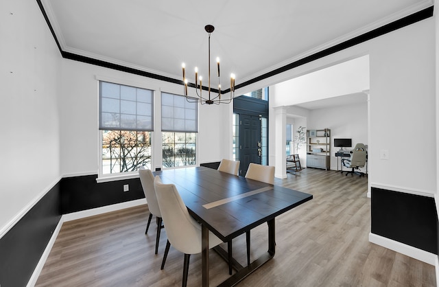 dining area with a notable chandelier, crown molding, and light hardwood / wood-style flooring