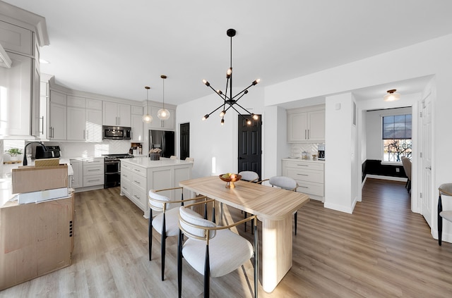 dining area with a notable chandelier, sink, and light hardwood / wood-style flooring