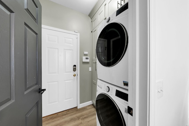 washroom featuring light hardwood / wood-style floors and stacked washer / drying machine