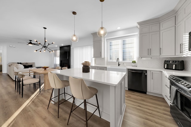 kitchen with electric range, sink, a center island, black dishwasher, and pendant lighting