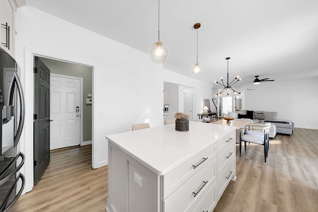 kitchen featuring ceiling fan with notable chandelier, a center island, decorative light fixtures, and white cabinetry