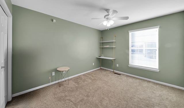 carpeted spare room with ceiling fan