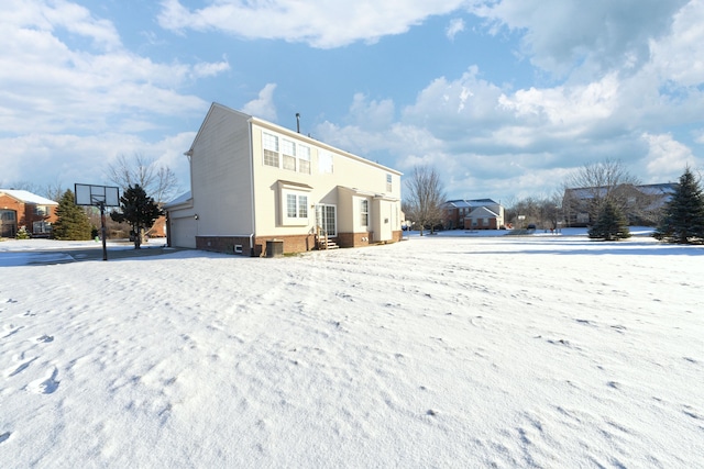 snow covered back of property featuring a garage