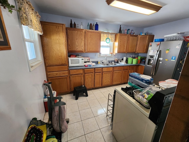 kitchen featuring stainless steel fridge, light tile patterned floors, and sink