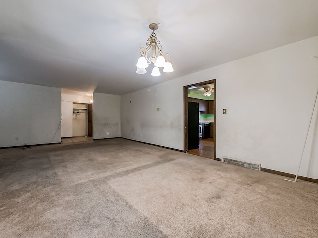 carpeted empty room featuring ceiling fan with notable chandelier