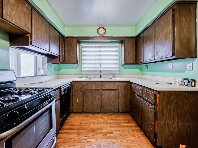 kitchen with gas range, black dishwasher, dark brown cabinetry, and sink