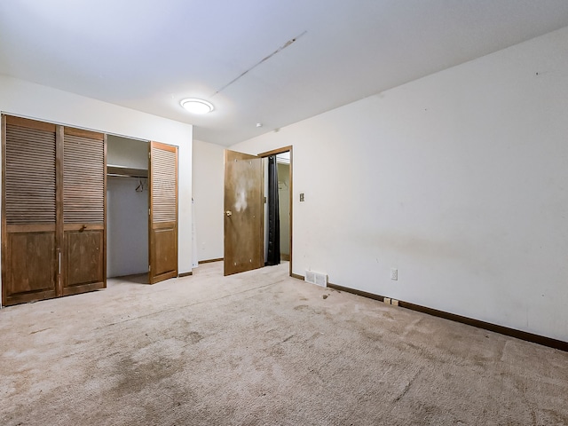 unfurnished bedroom featuring light colored carpet and a closet