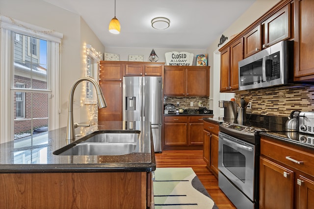 kitchen featuring pendant lighting, tasteful backsplash, a kitchen island with sink, appliances with stainless steel finishes, and sink