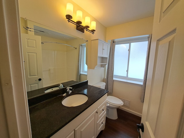 bathroom featuring toilet, wood-type flooring, vanity, and walk in shower