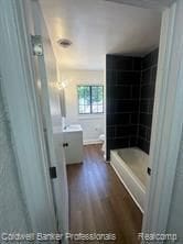 bathroom with wood-type flooring, vanity, and tiled shower