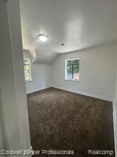 bonus room with vaulted ceiling and carpet flooring