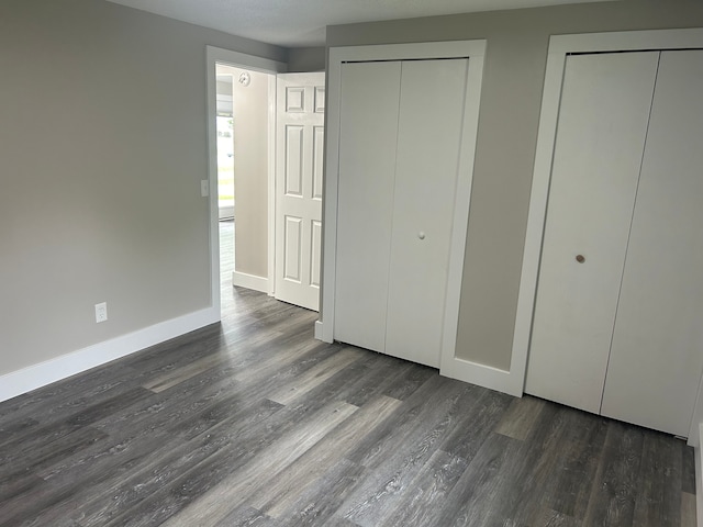 unfurnished bedroom with multiple closets and dark hardwood / wood-style flooring