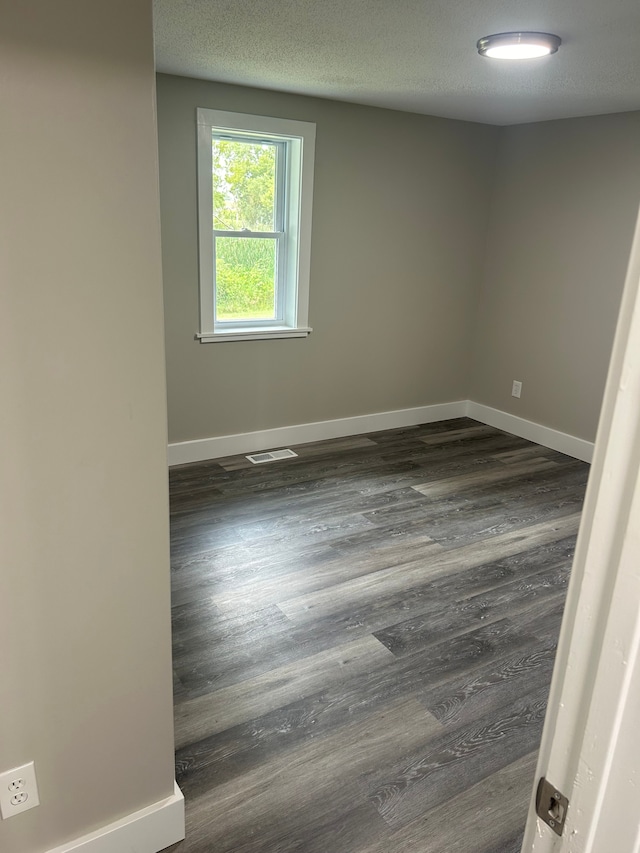 unfurnished room with a textured ceiling and dark hardwood / wood-style floors